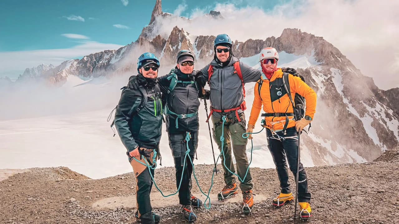 Four smiling mountaineers on the summit of Mont Blanc, ready for an unforgettable adventure.