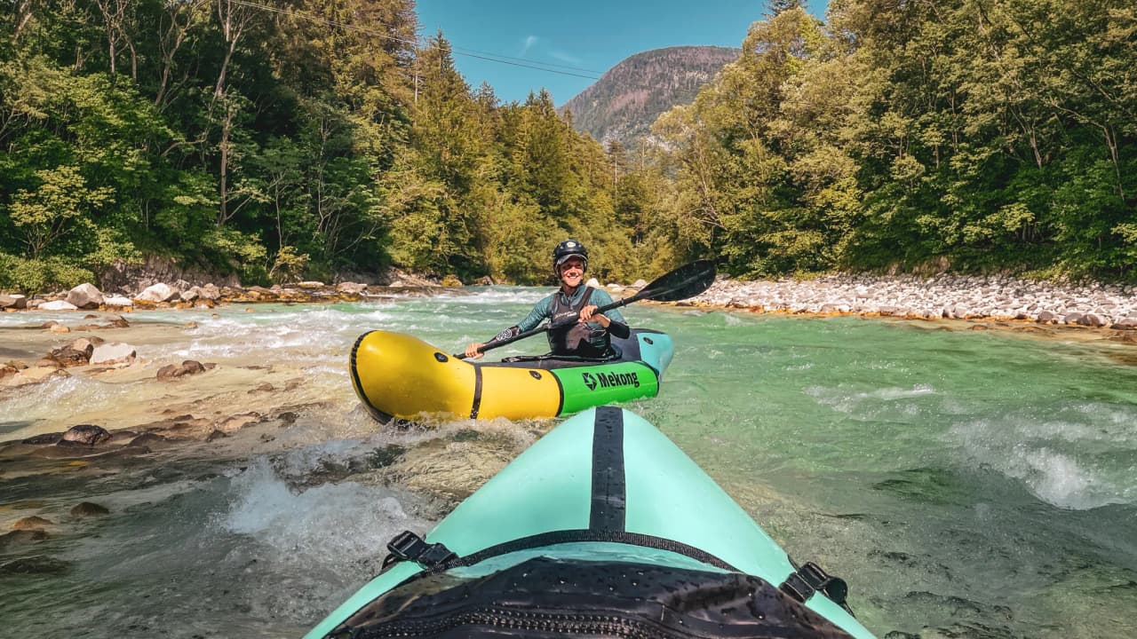 Two packrafts glide down a turquoise alpine river, surrounded by lush green forests. Adventure in the heart of the Slovenian landscape!