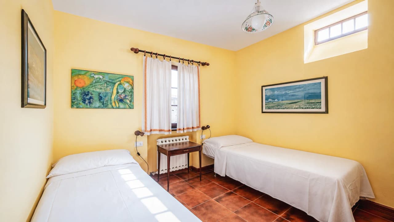 A cosy room with yellow walls, two beds, a soothing view and artistic décor – ideal for travellers.