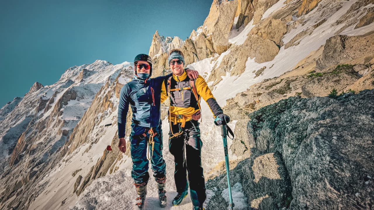 Two smiling adventurers pose on an enchanting glacier, surrounded by majestic mountains.