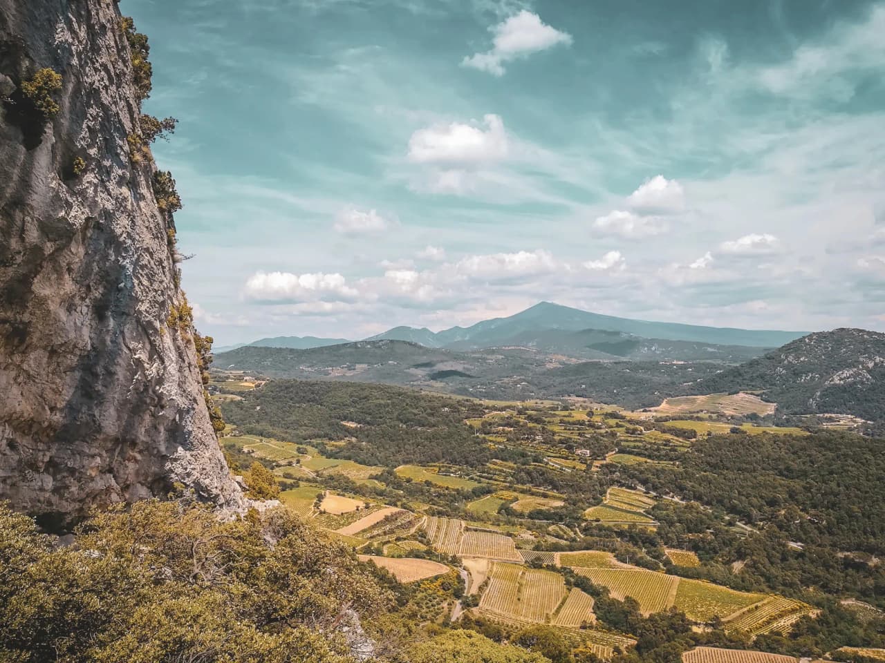 Vue panoramique du Mont Ventoux, vallées verdoyantes et ciel lumineux invitent à l'aventure.