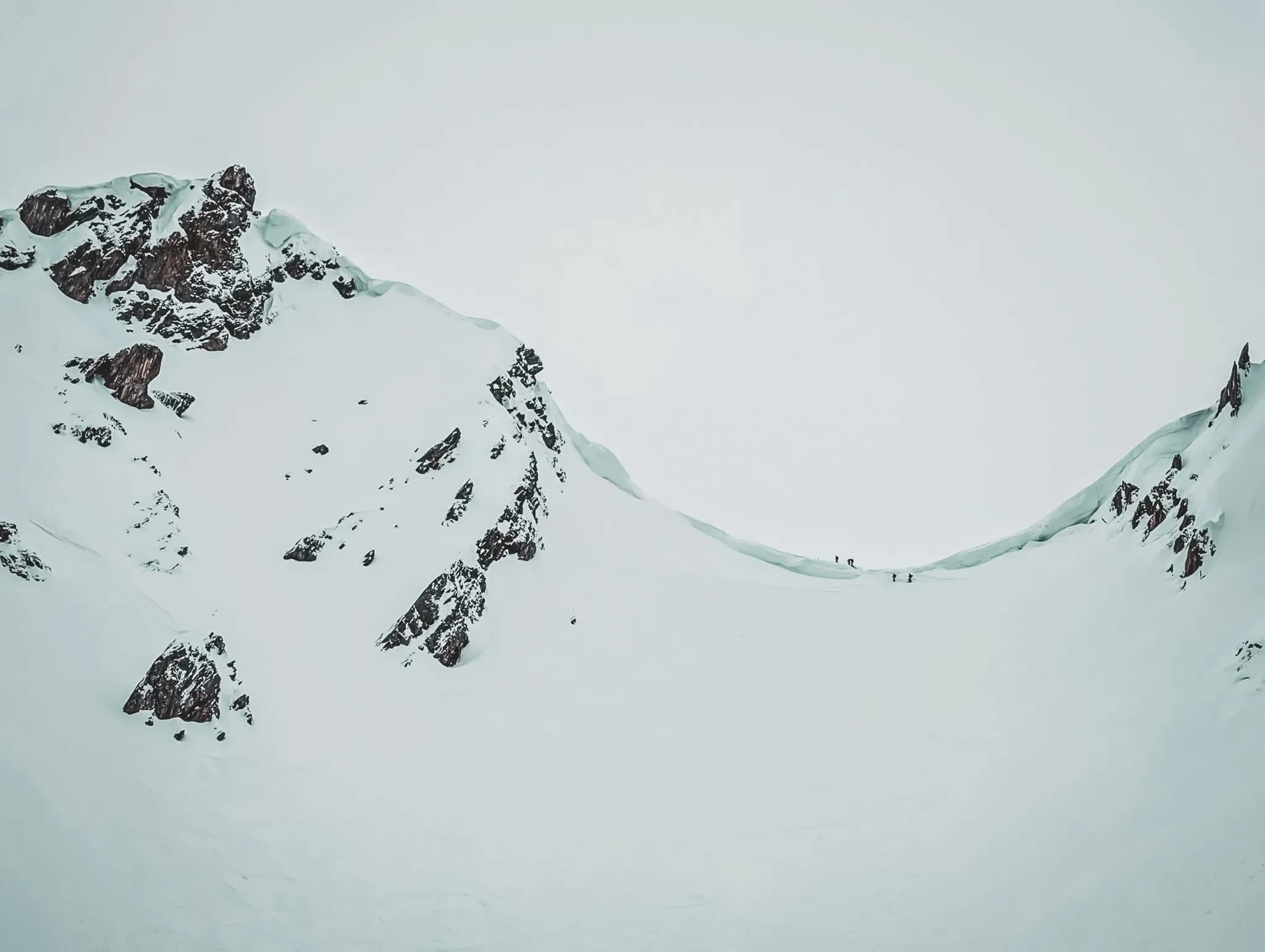 Skiers on a snowy plateau, surrounded by majestic mountains.