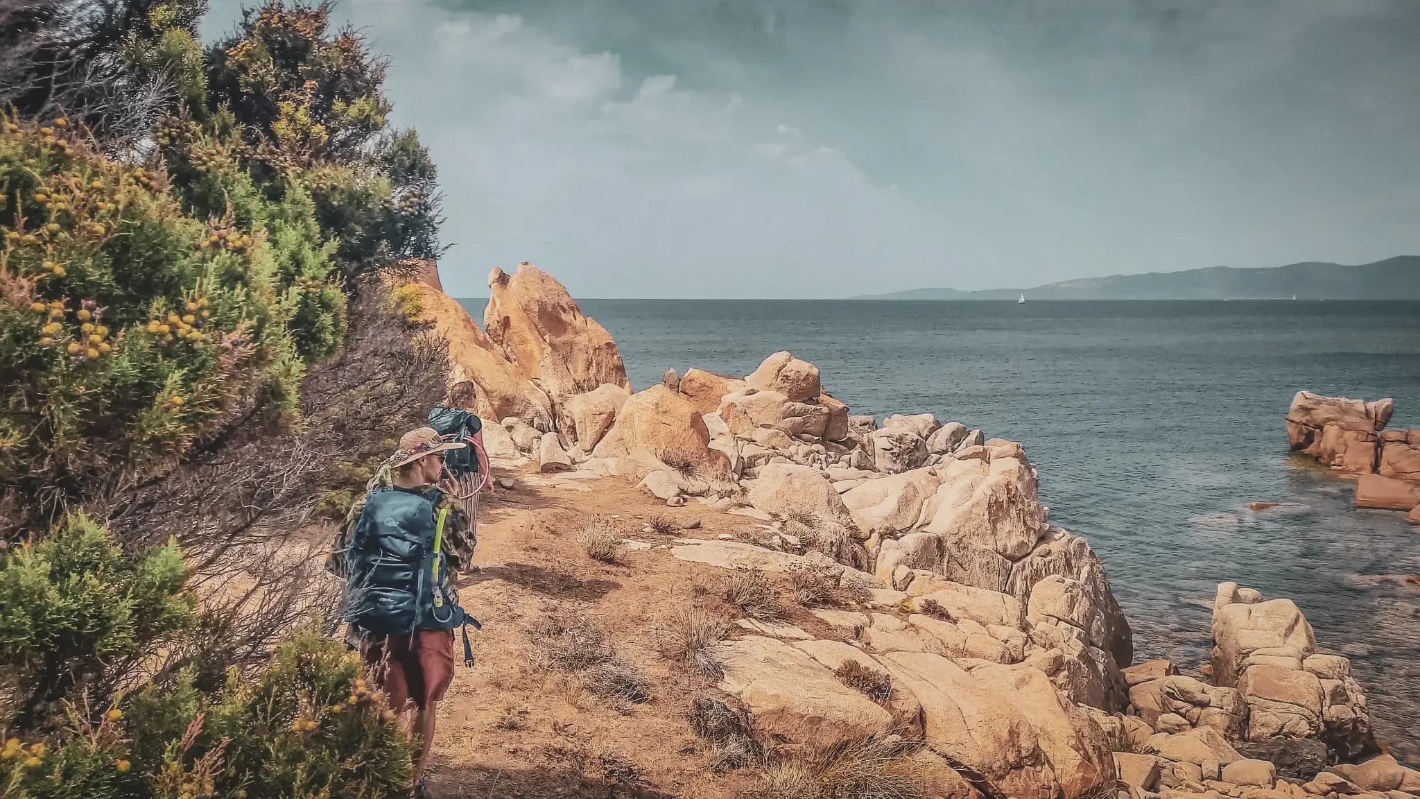 Des randonneurs explorent des criques sauvages et des rochers en bord de mer en Corse du Sud.