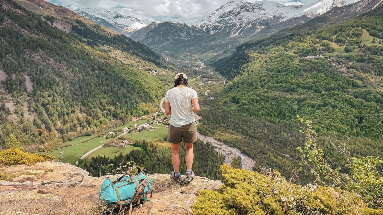 A majestic view of the Écrins mountains, combining greenery and cloudy skies, a call to adventure.