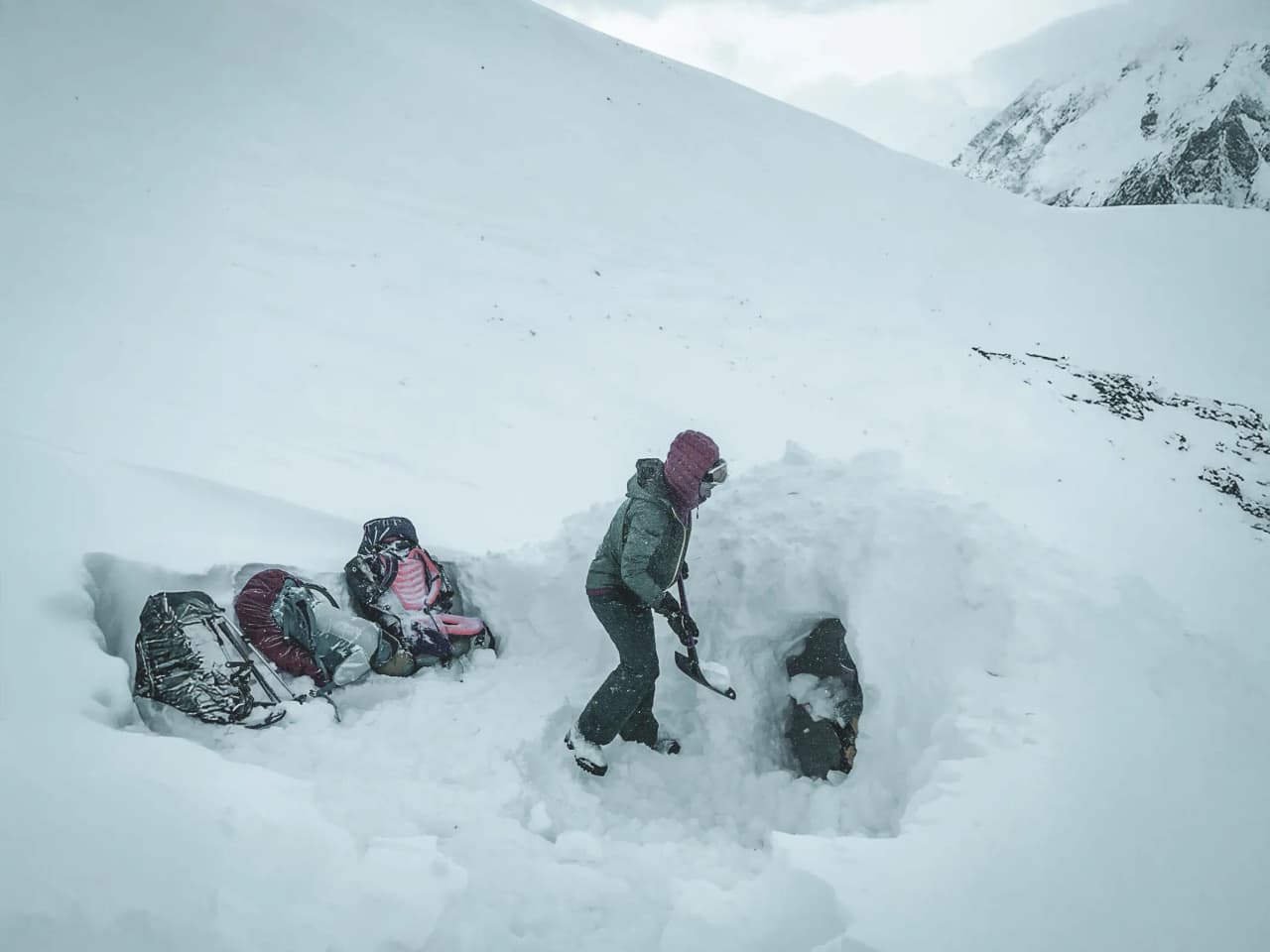 Un aventurier creuse un igloo dans un paysage enneigé majestueux, prêt pour une nuit magique.