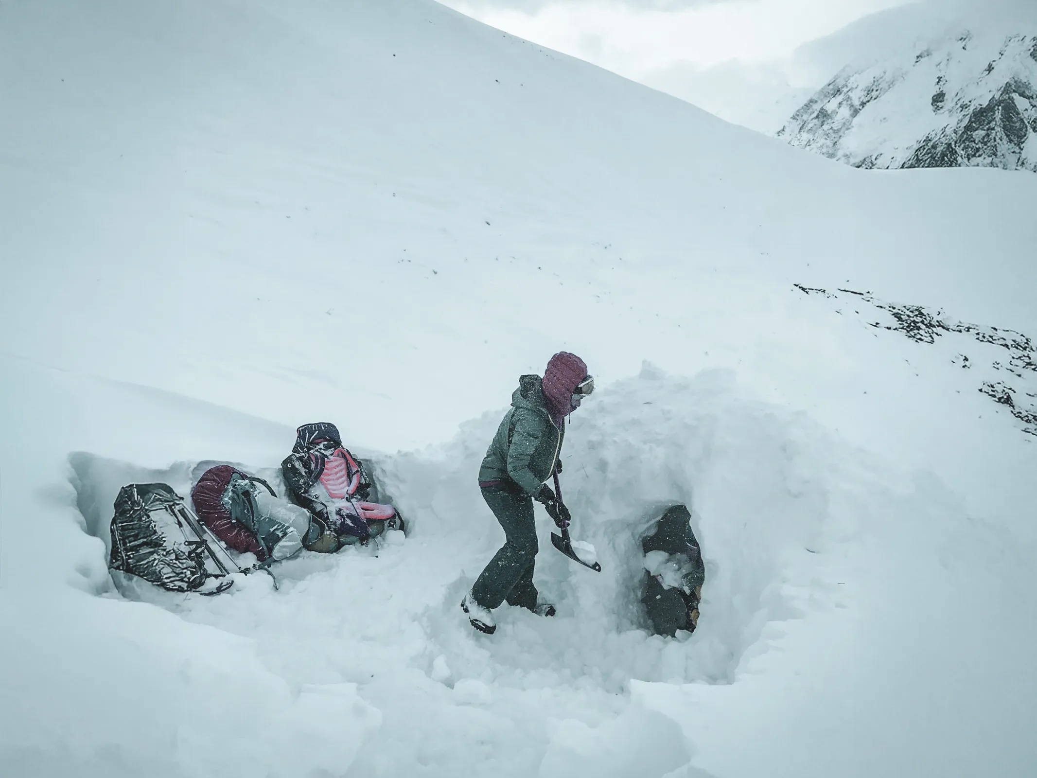 Un aventurier creuse un igloo dans un paysage enneigé majestueux, prêt pour une nuit magique.