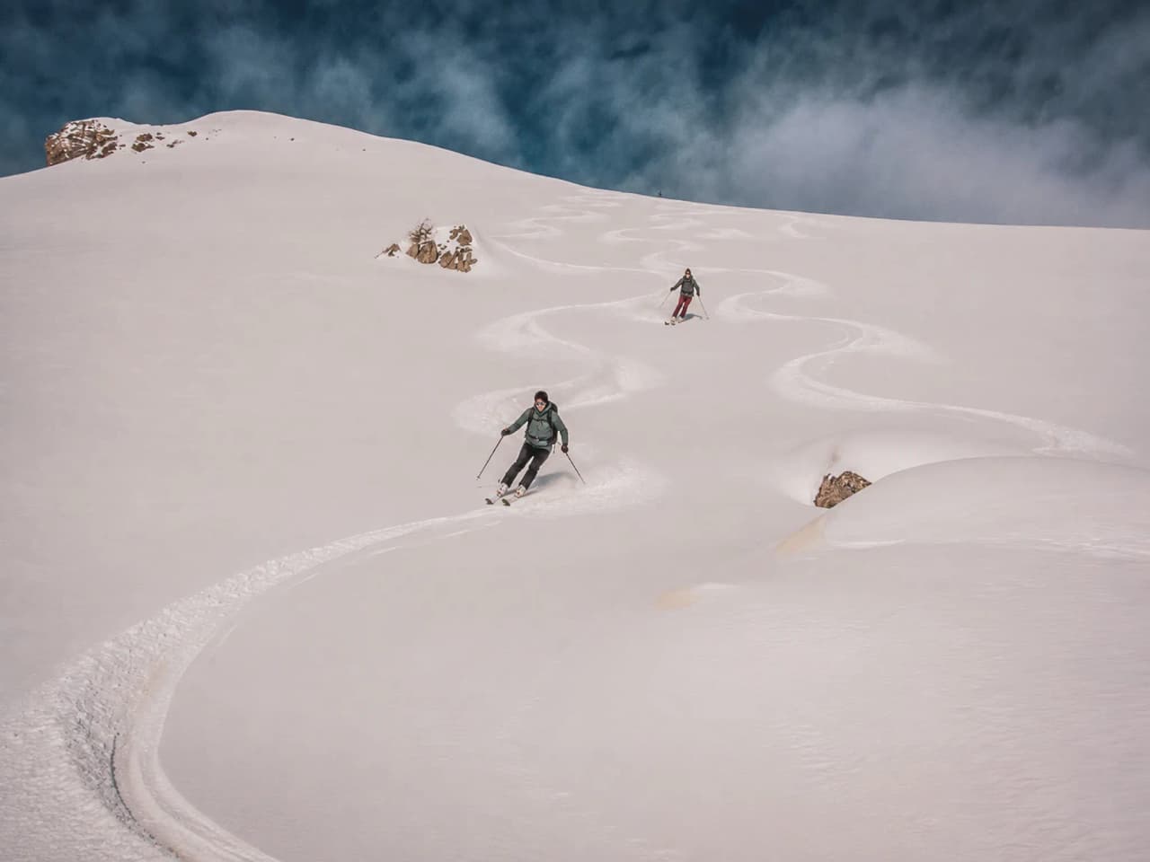 Skiers hurtling down vast snow-covered slopes in the Écrins, amidst breathtaking scenery.