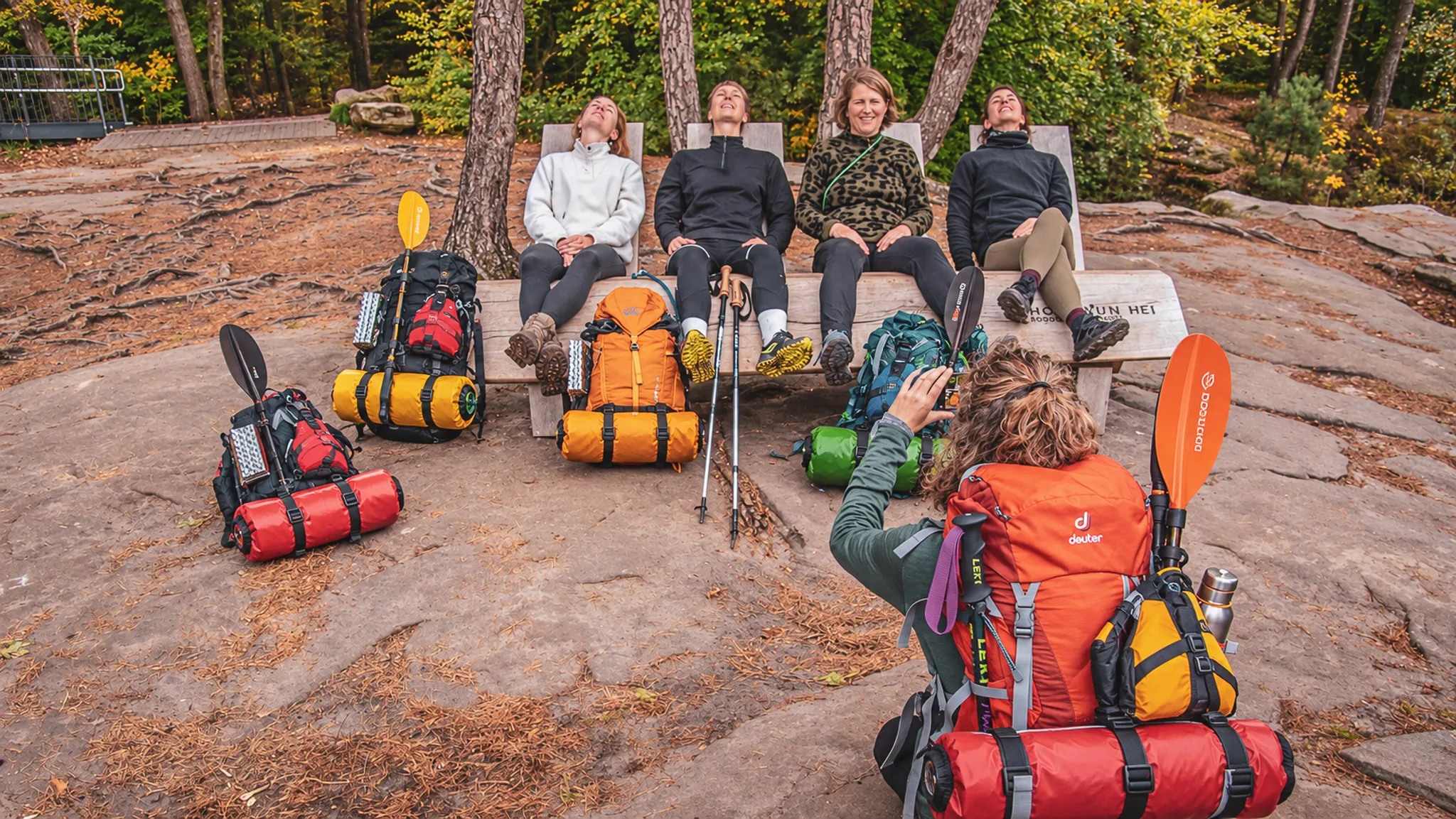 Groupe de randonneurs se reposant en nature, entourés de sacs à dos colorés après une aventure.