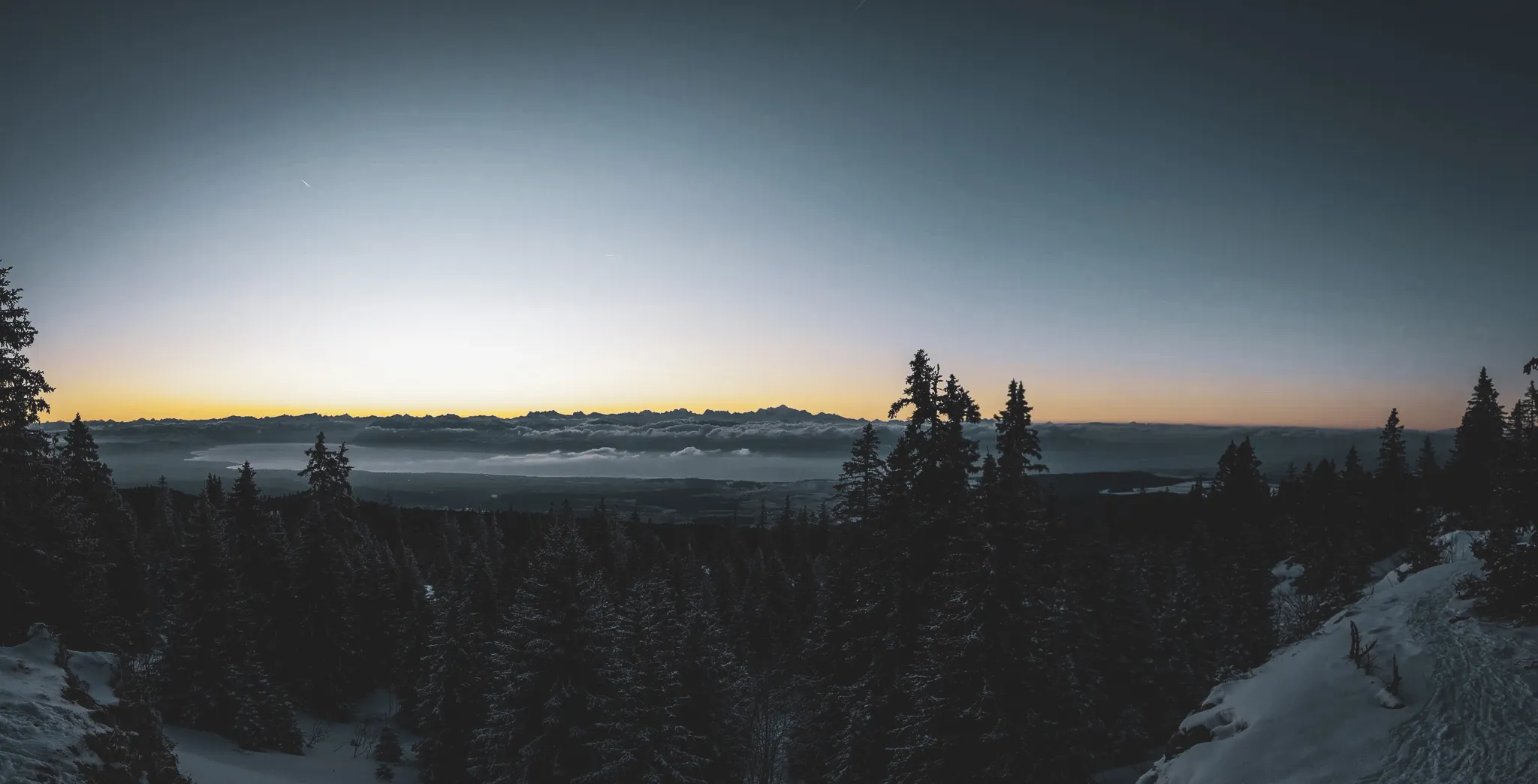 Snow-covered panoramas of the Jura, majestic forests and mountains at twilight invite adventure.