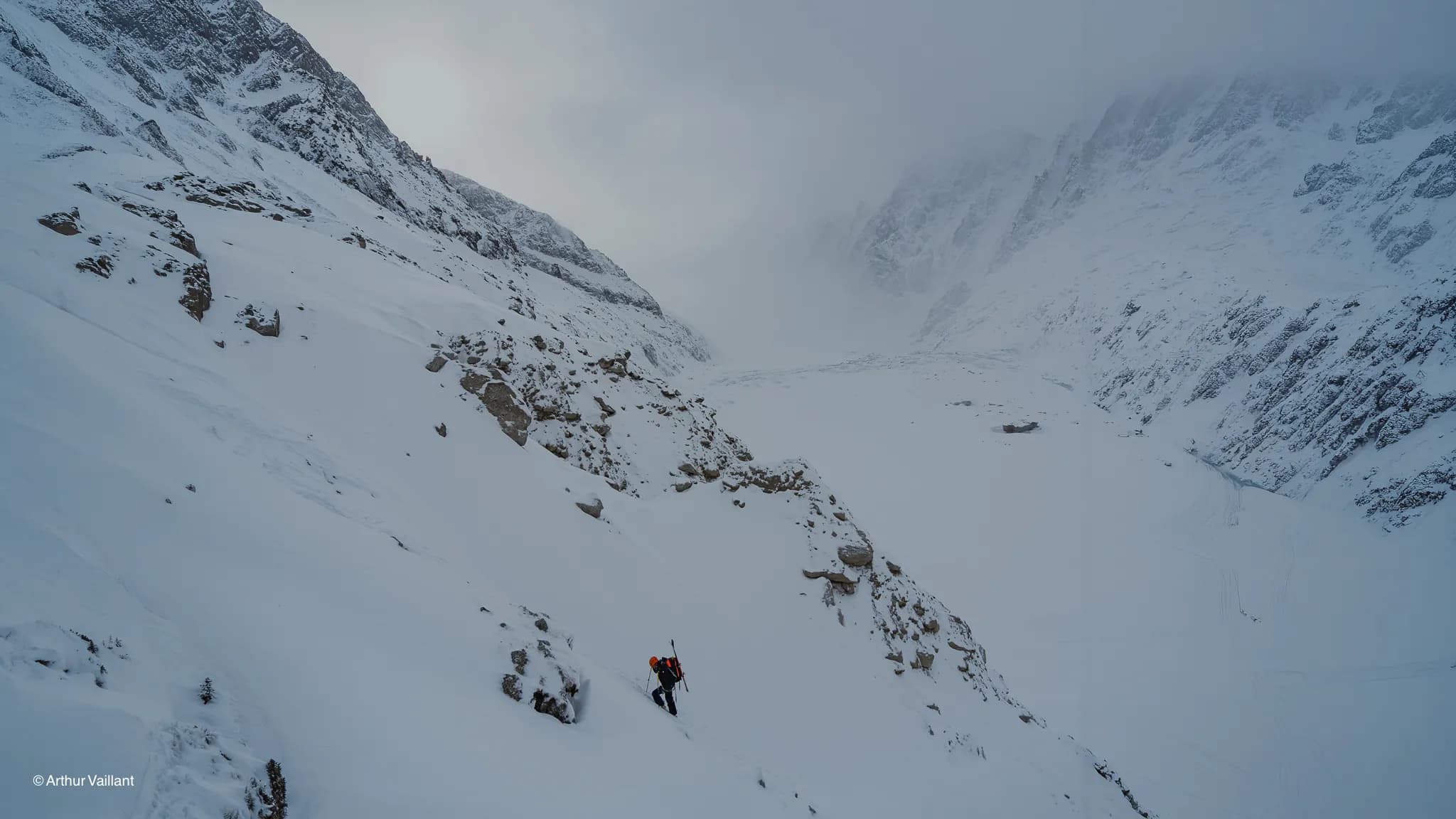 A lone skier braving the glaciers beneath a misty sky; an enchanting alpine landscape.