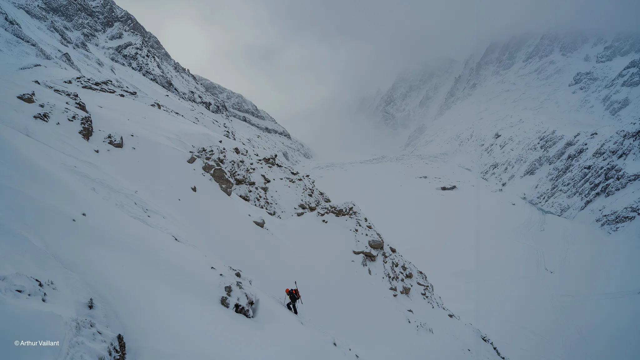 A lone skier braving the glaciers beneath a misty sky; an enchanting alpine landscape.