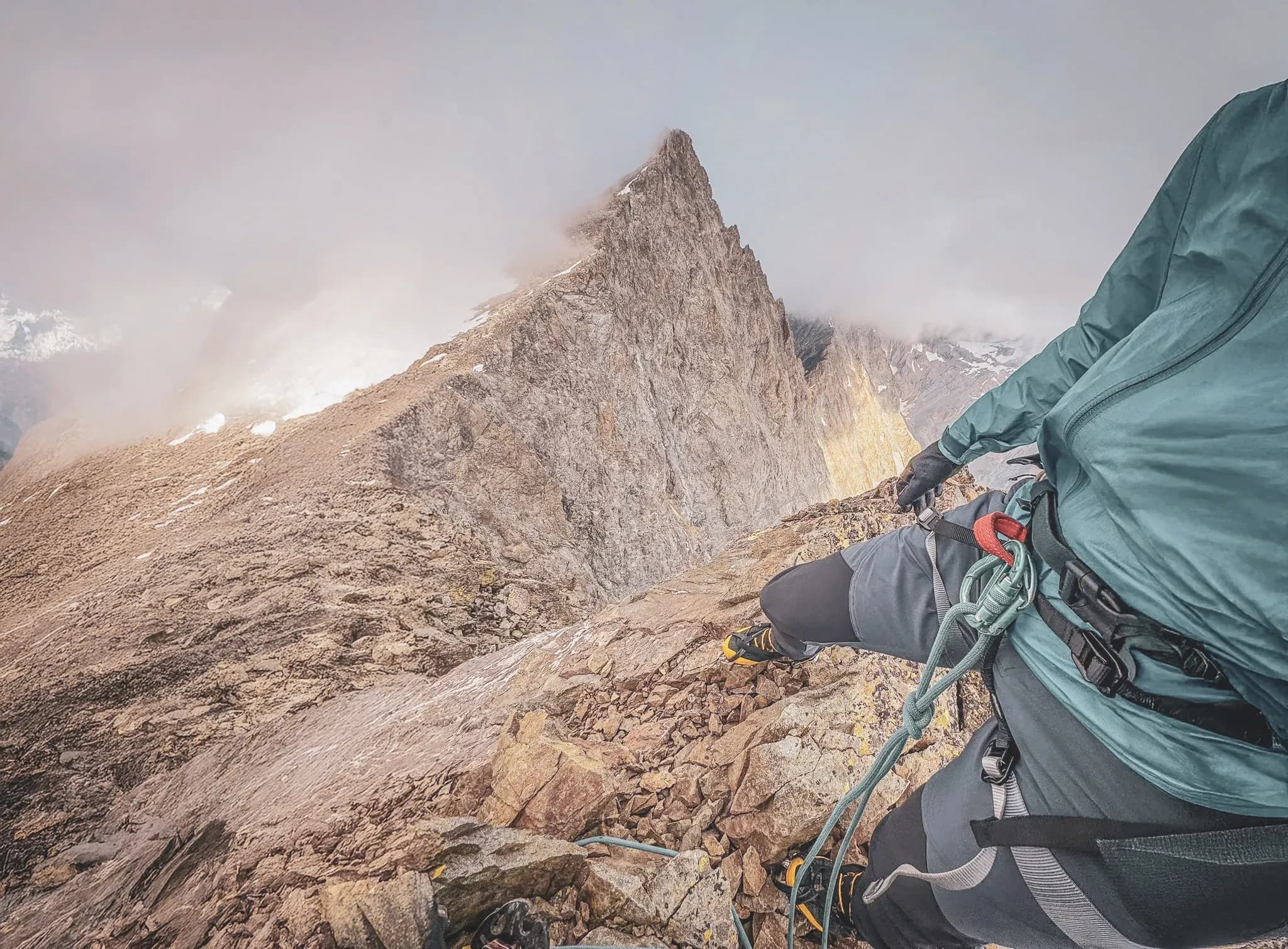 A climber on a rocky ridge with a spectacular view of the Écrins.