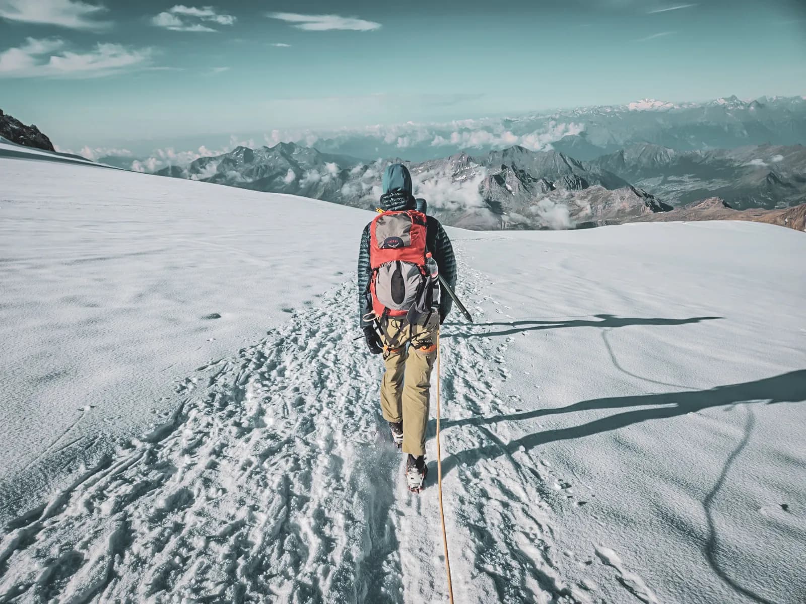 An advanced mountaineer on a summit glacier, surrounded by breathtaking mountain scenery.