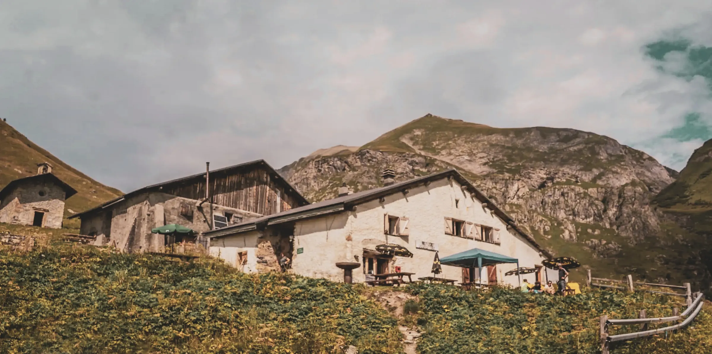 Een Berghut omgeven door groen, met uitzicht op de majestueuze toppen van de Alpen. Ontsnapping gegarandeerd!