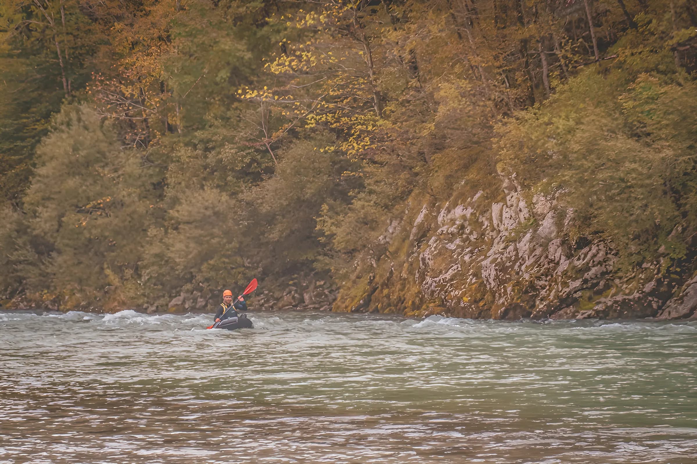 Packraft hiker in the distance in a yellowish Slovenian river