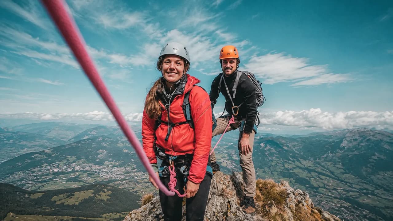 Alpinistes souriants sur un sommet des Pyrénées, avec vue panoramique spectaculaire.