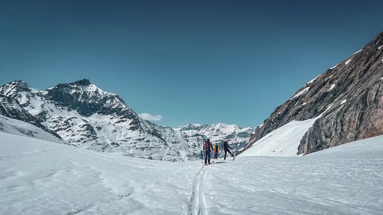 Ski touring on a sun-drenched glacier, surrounded by majestic snow-capped mountains.