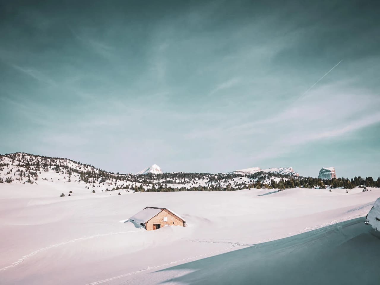 Een besneeuwd landschap in de Vercors, met een rustiek chalet en majestueuze bergtoppen op de achtergrond.