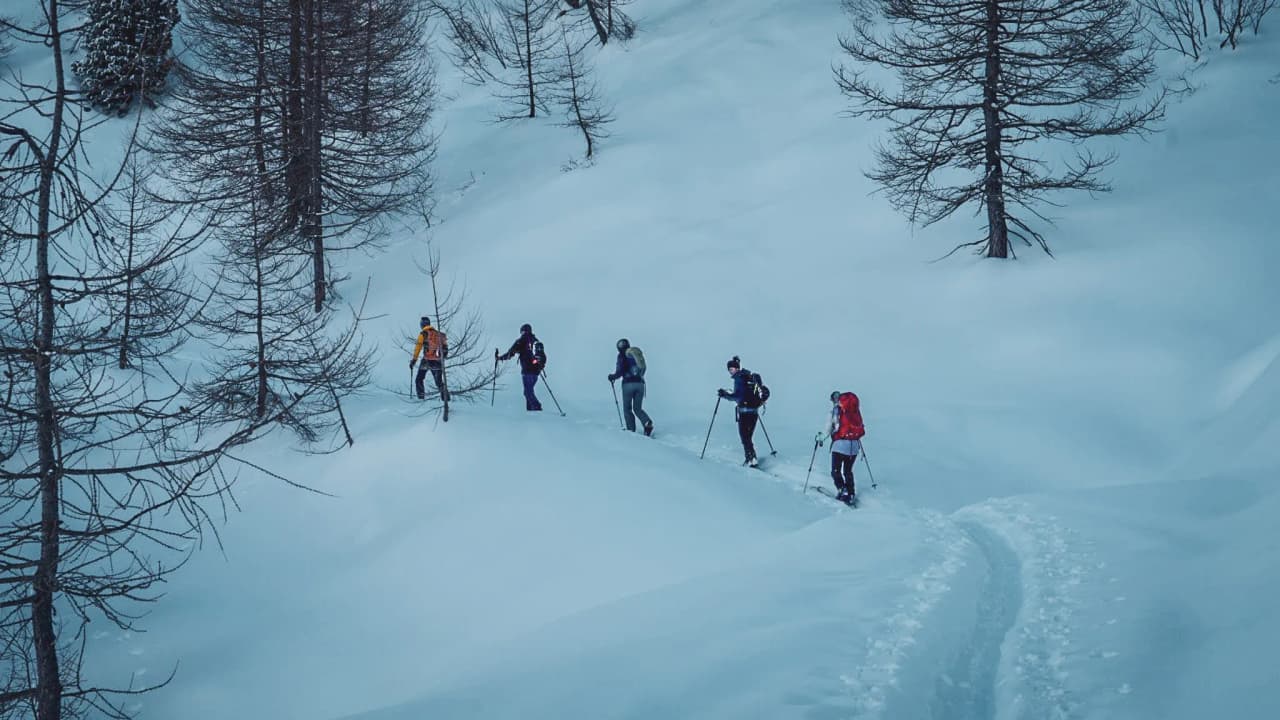 Skiers make their way along a snow-covered trail, surrounded by enchanting Alpine scenery.