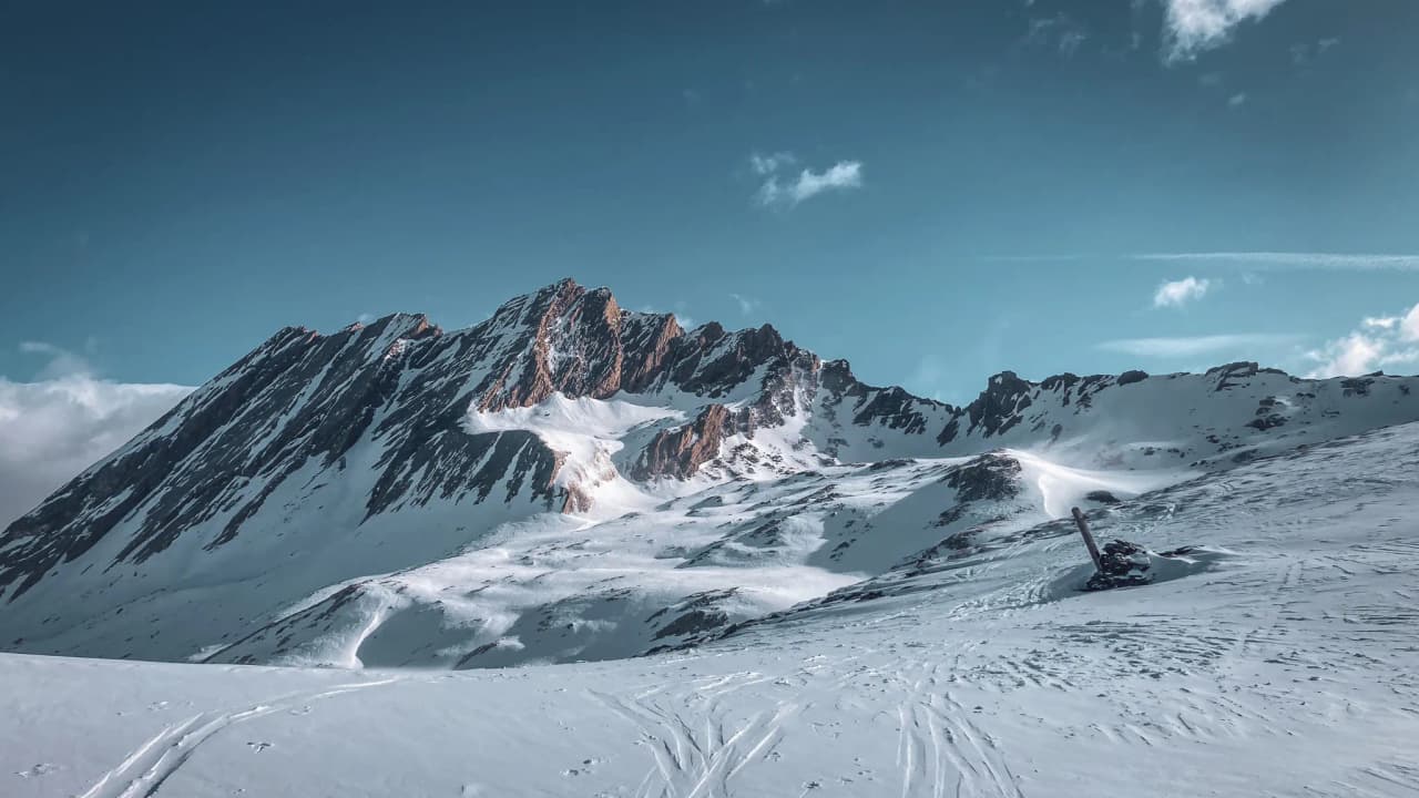 Majestueuse montagne enneigée sous un ciel bleu éclatant, invitation à l'aventure alpine.
