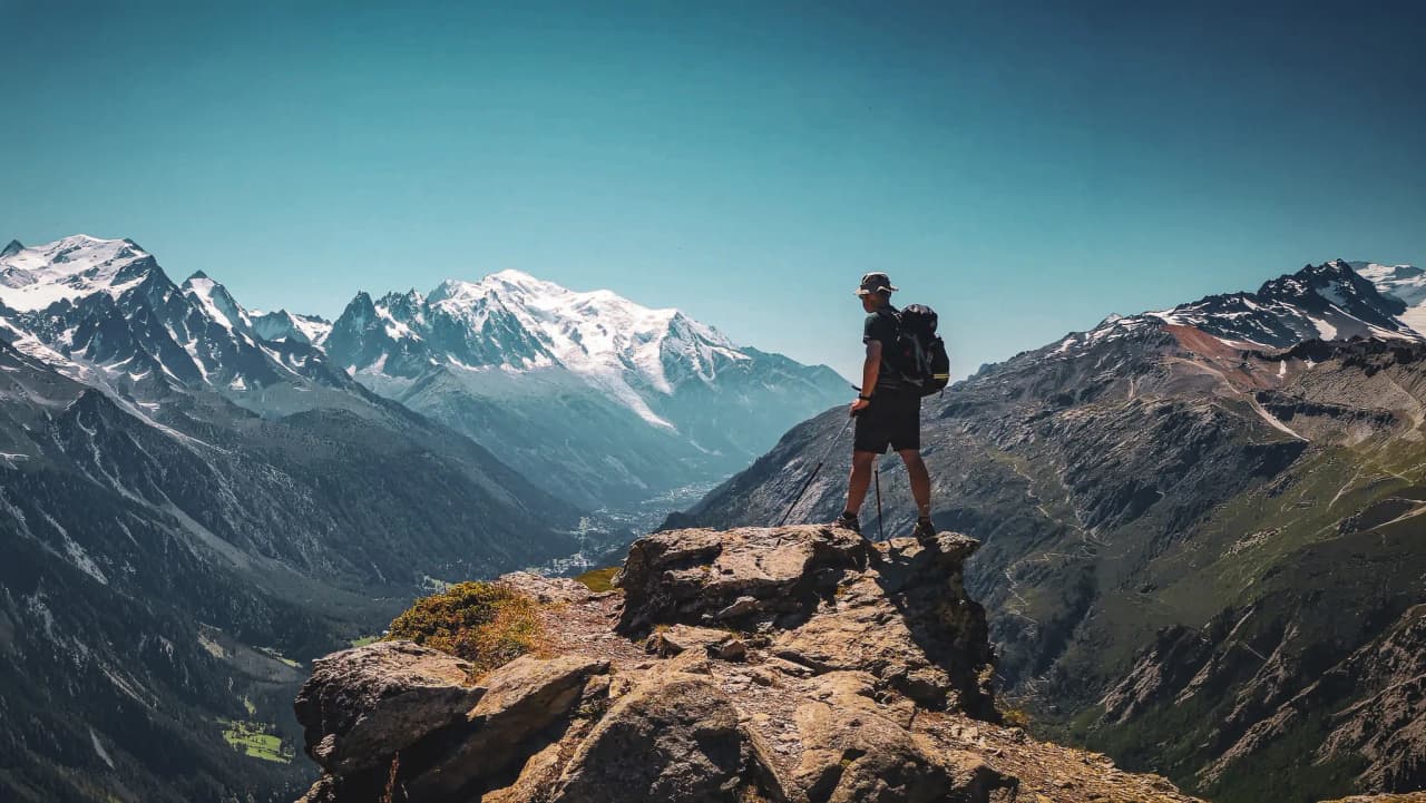 Een man die majestueuze pieken, bergen en indrukwekkende landschappen aanschouwt.