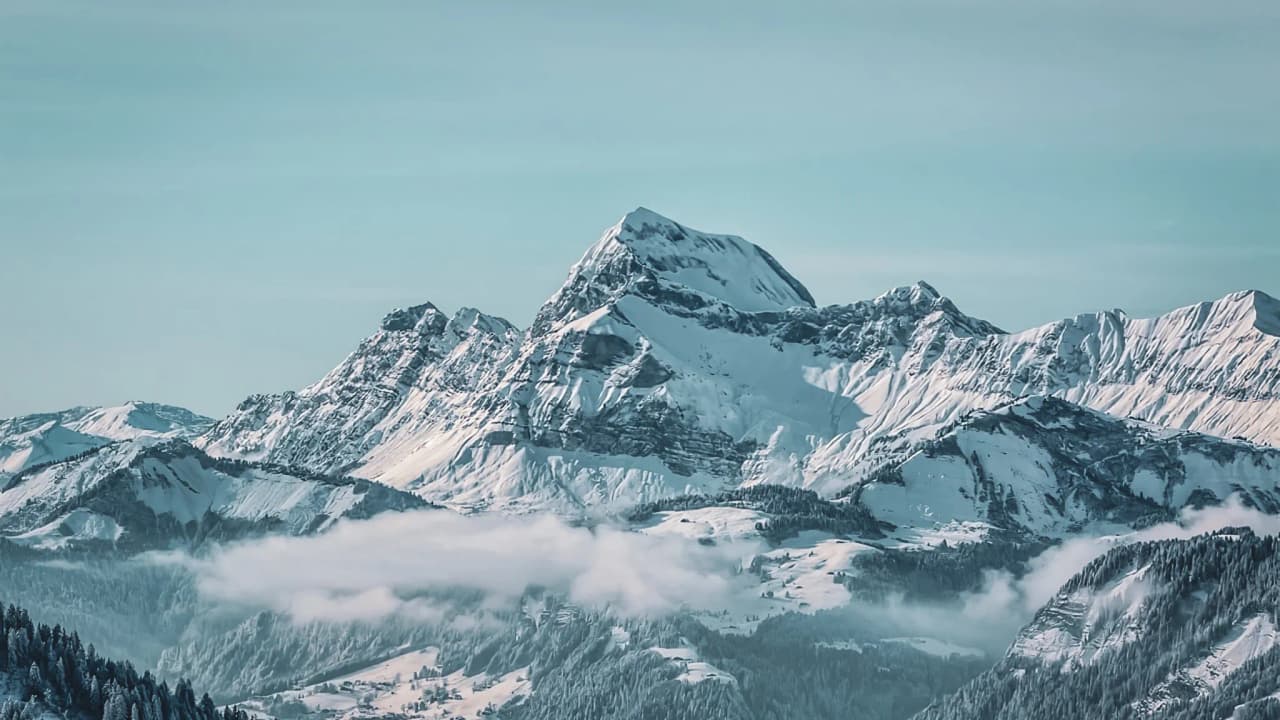 A majestic mountain landscape with snow-capped peaks and a bright sky, an invitation to adventure.