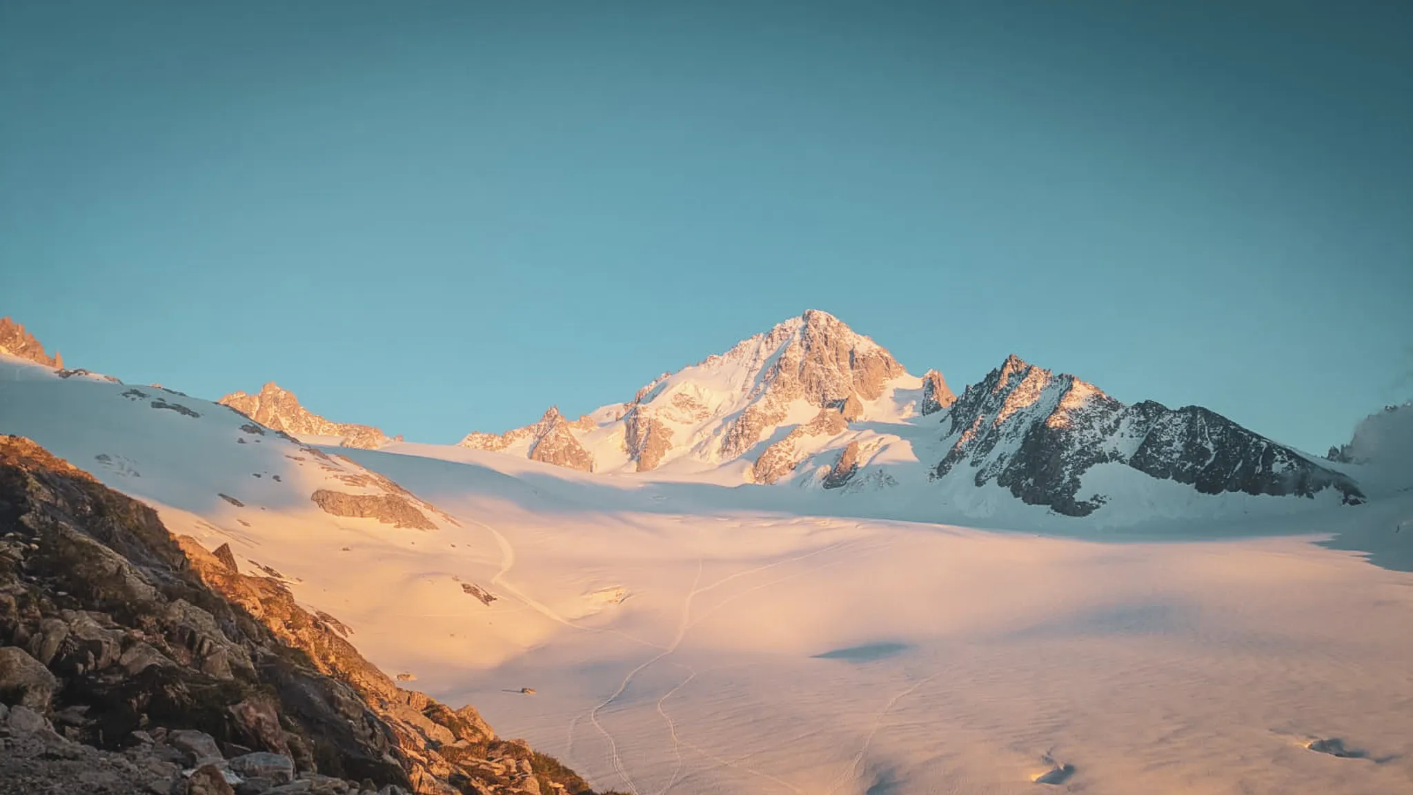 Majestueux sommet du Mont Blanc sous un ciel bleu, illuminé par les premiers rayons du soleil.
