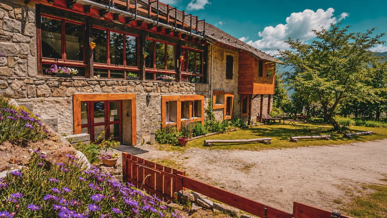 Gîte en pierre au cœur des Pyrénées, entouré de fleurs et avec vue sur la nature verdoyante.