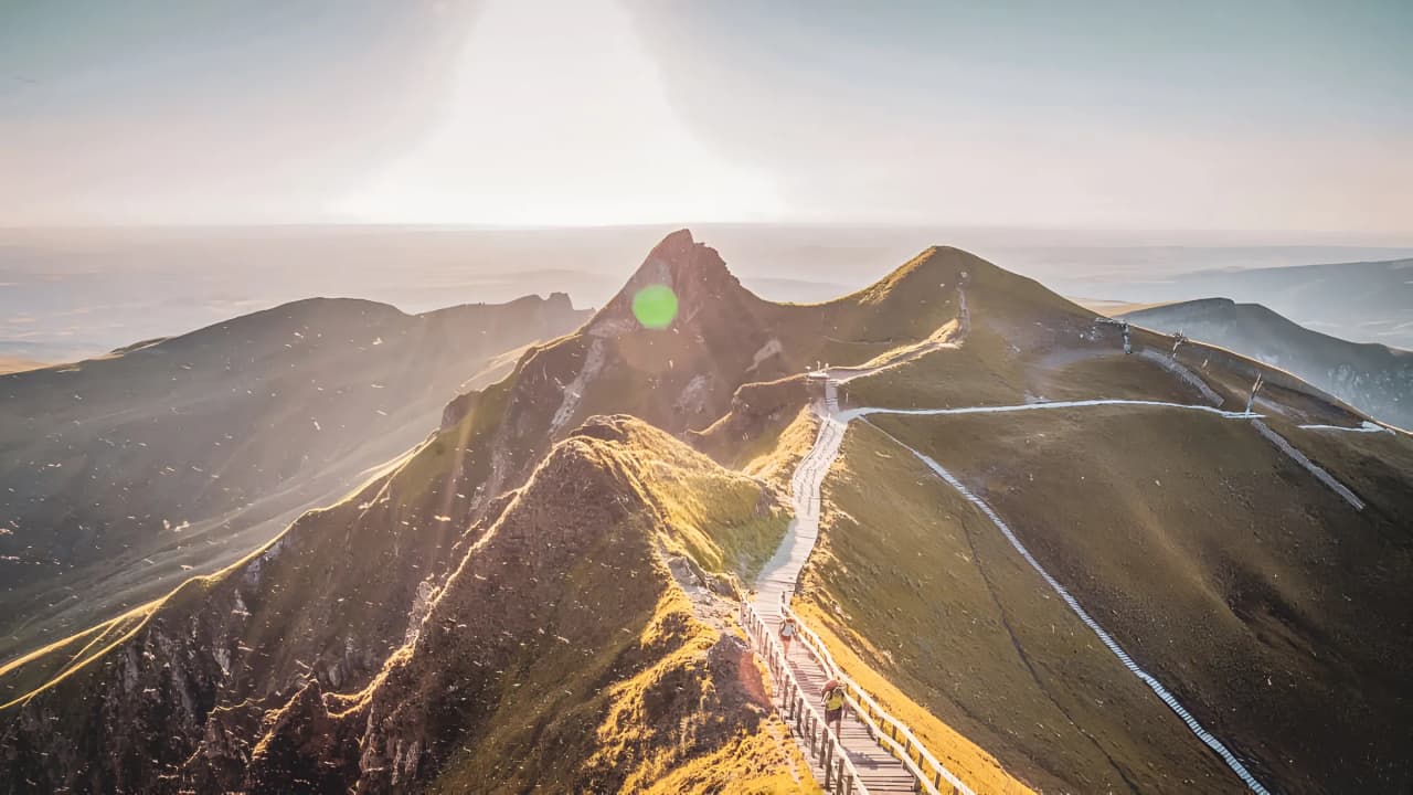 Panoramic view of the volcanic ridges of the Massif Central, illuminated by the sun.