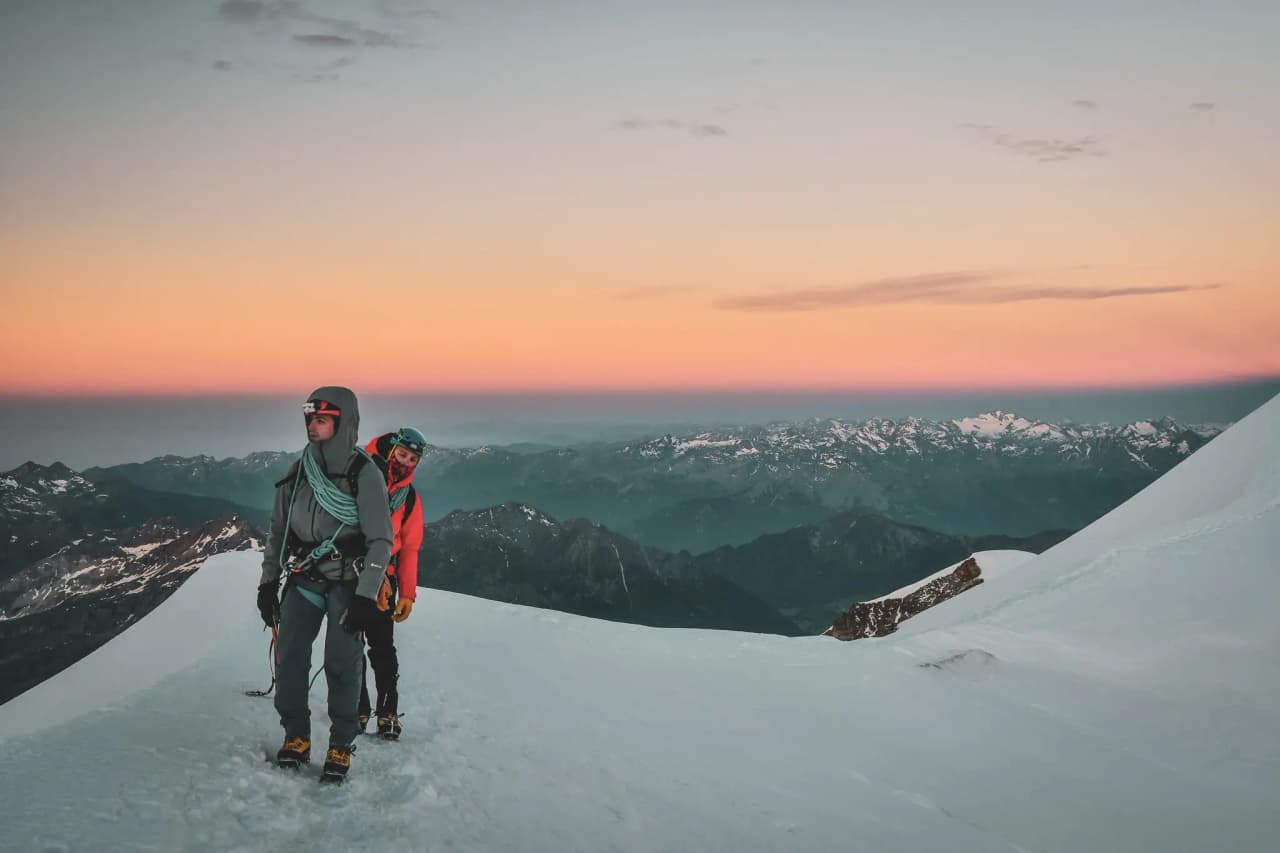 Aventuriers sur un glacier, admirant le lever du soleil sur les sommets majestueux.