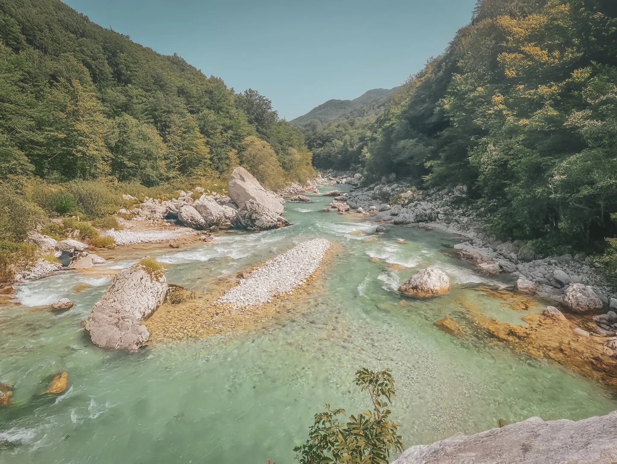 A turquoise river meandering between rocks and green forests in Slovenia, an invitation to adventure.