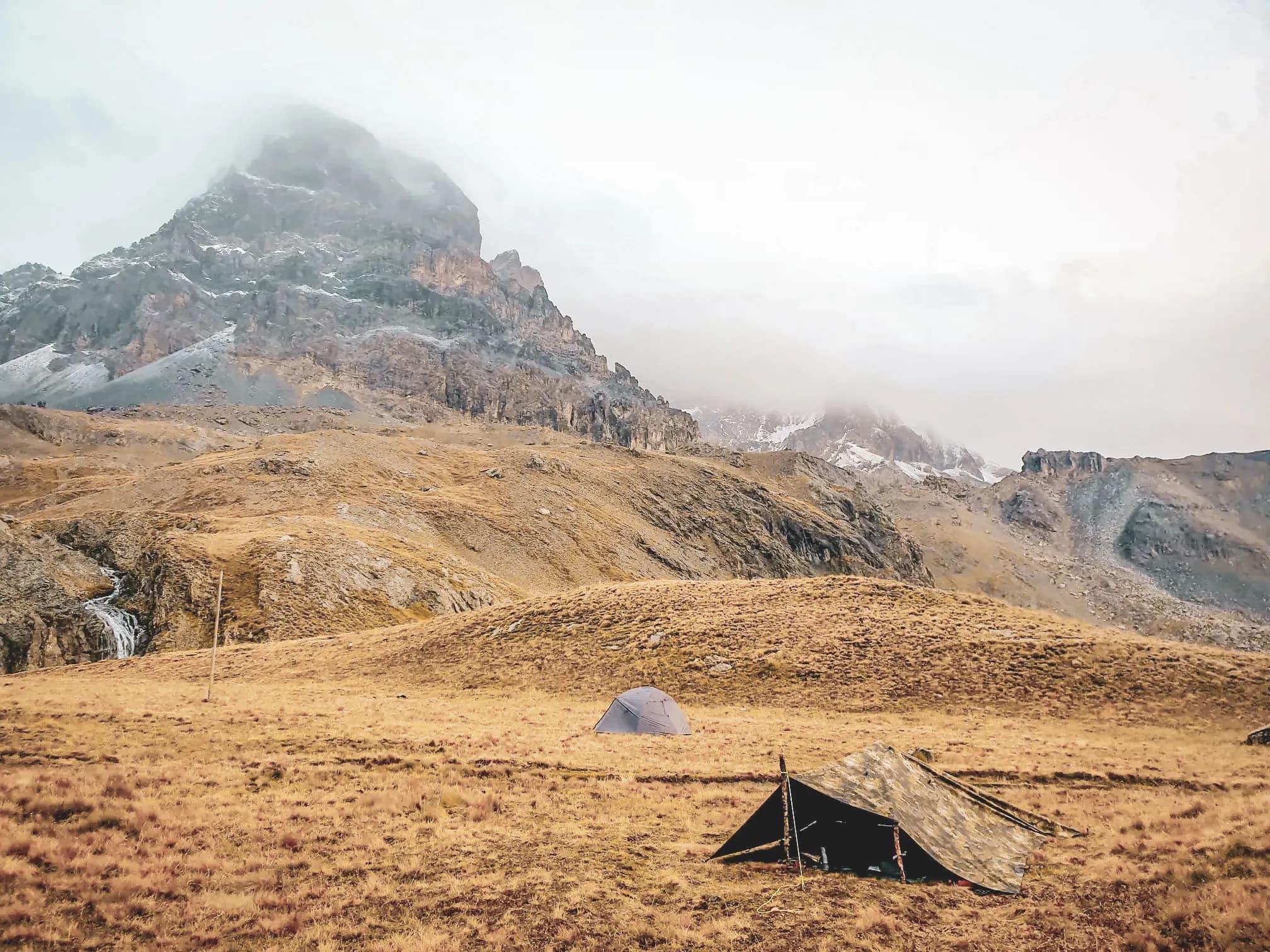 Een majestueus alpenlandschap met tenten aan de voet van bergreuzen, een uitnodiging tot avontuur.
