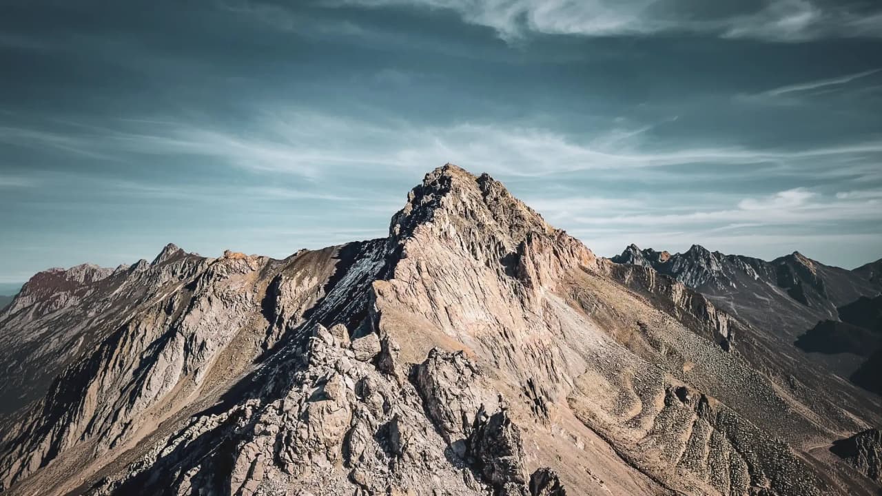 Een majestueuze woestijntop onder een bewolkte hemel, een uitnodiging voor alpien avontuur.
