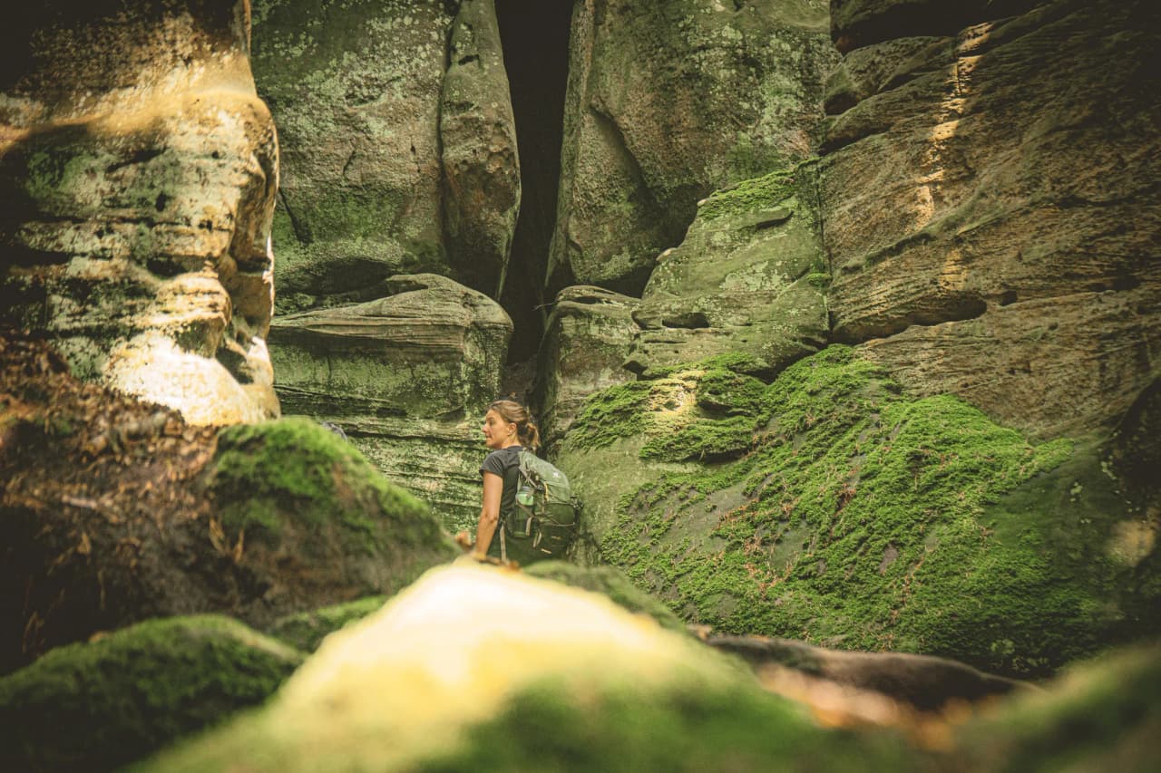A hiker marvelling at the mossy rocks in Luxembourg's Little Switzerland.