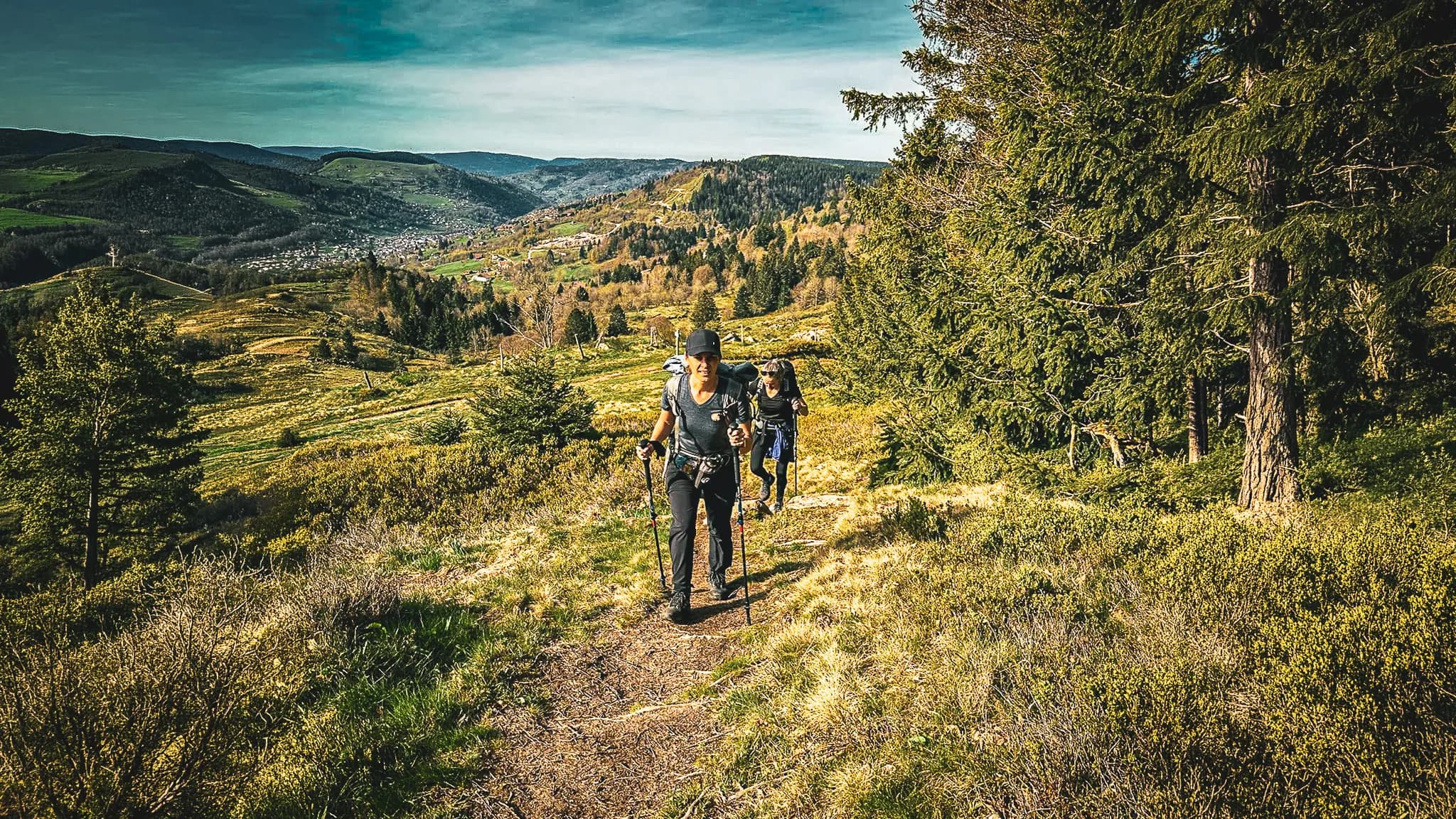 Groupe de randonneurs sur un sentier verdoyant dans les Vosges, entourés de paysages pittoresques.