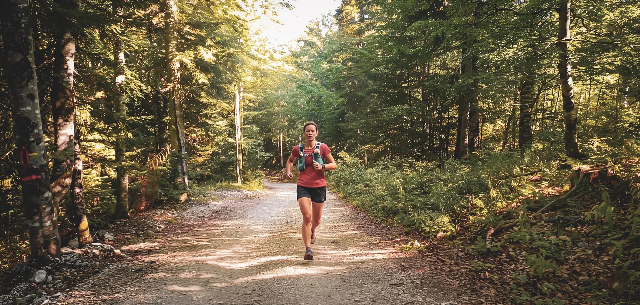 Vrouw hardlopend op een zonnig bospad, omgeven door groen in de Vercors.