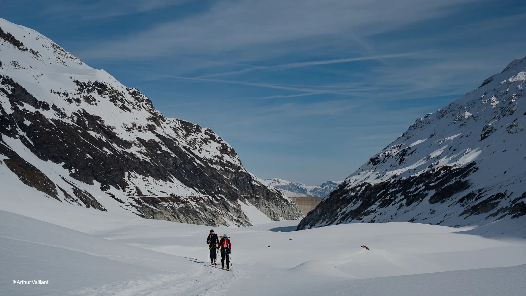 Two skiers are making their way through an enchanting alpine landscape, surrounded by majestic peaks and pristine snow.