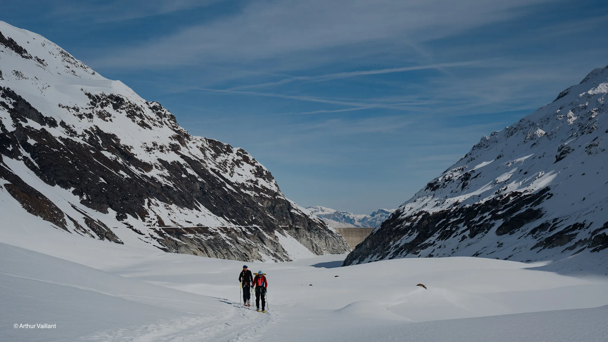 Two skiers are making their way through an enchanting alpine landscape, surrounded by majestic peaks and pristine snow.