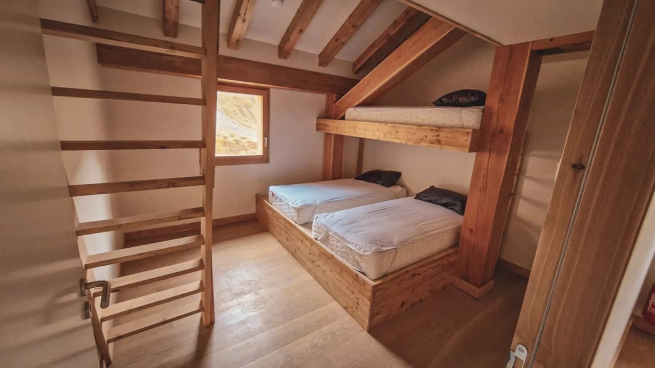 Warm wooden room with bunk beds, natural light and mountain views.
