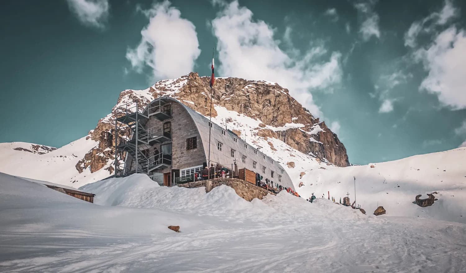 Refuge alpin au pied du Grand Paradis, entouré de neige et montagnes, invitation à l'aventure.