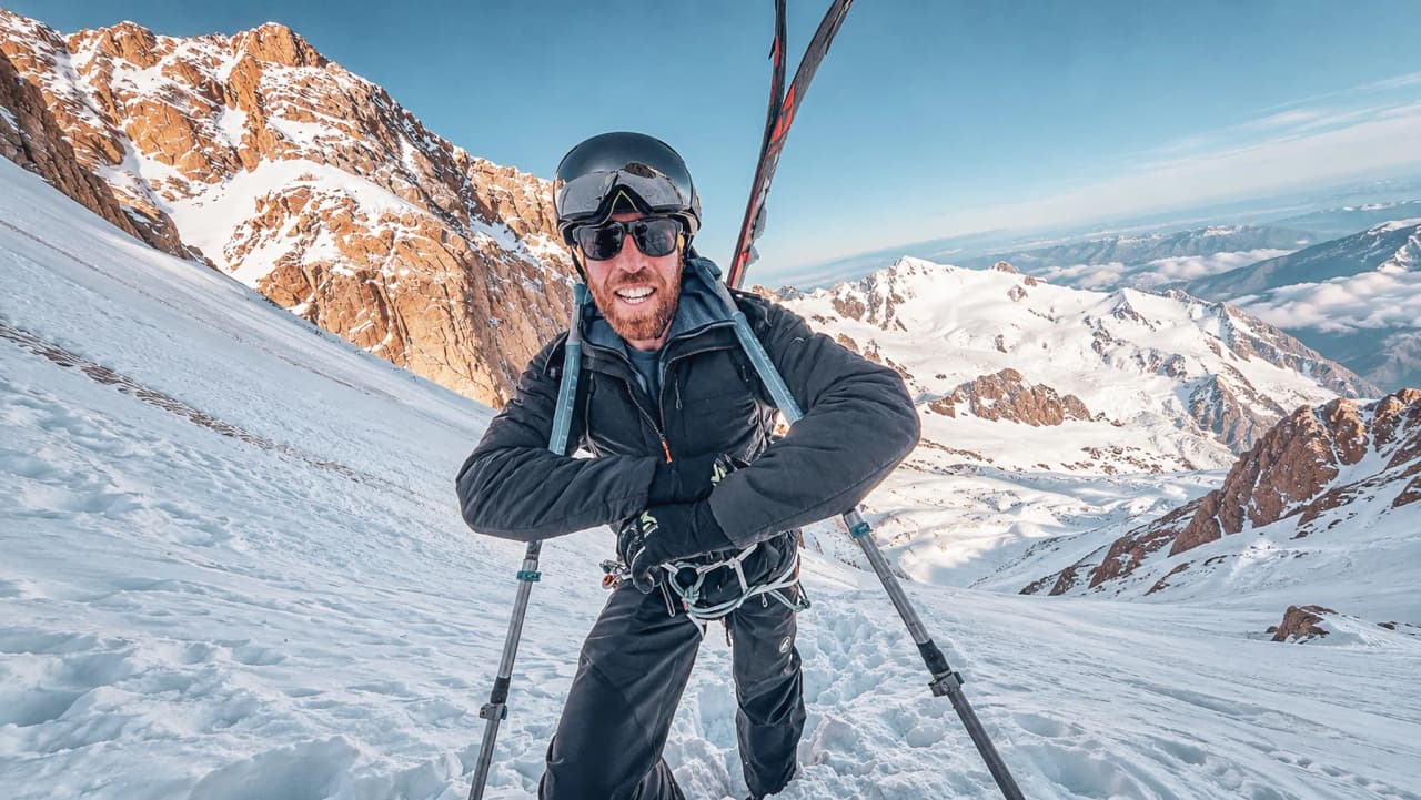 Un aventurier souriant en ski de randonnée sur les pentes enneigées du Mont Blanc.