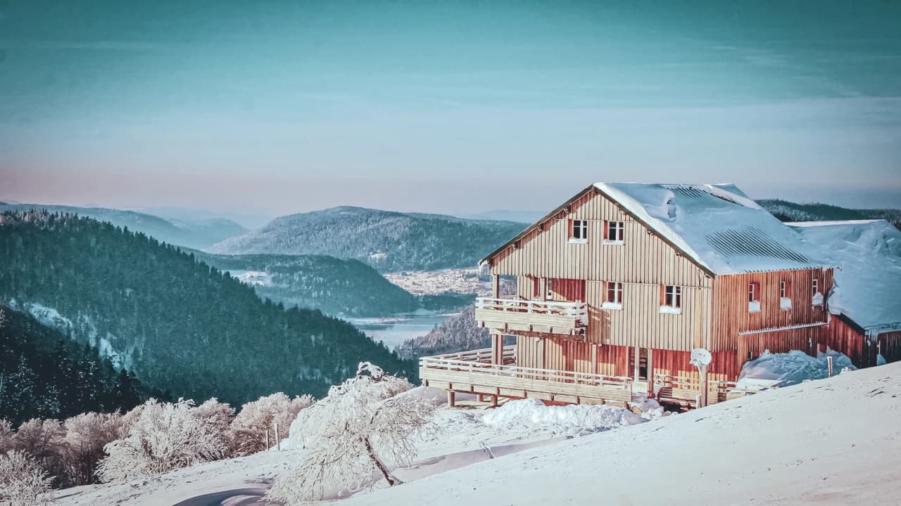 Een besneeuwd houten Berghut met een prachtig uitzicht op de Vogezen.