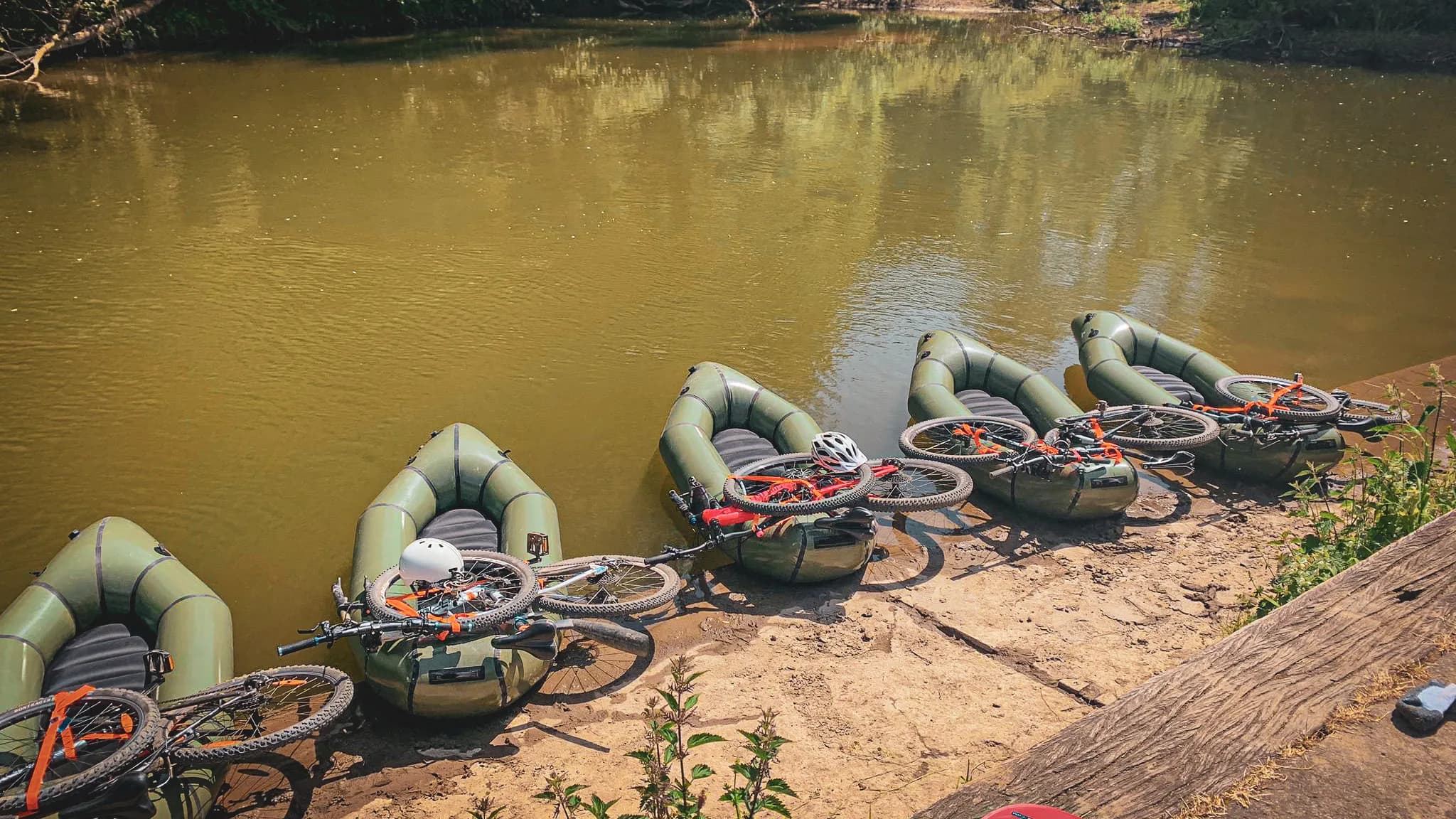 Vélos sur des packrafts au bord de la Lesse, invitation à l'aventure en pleine nature.
