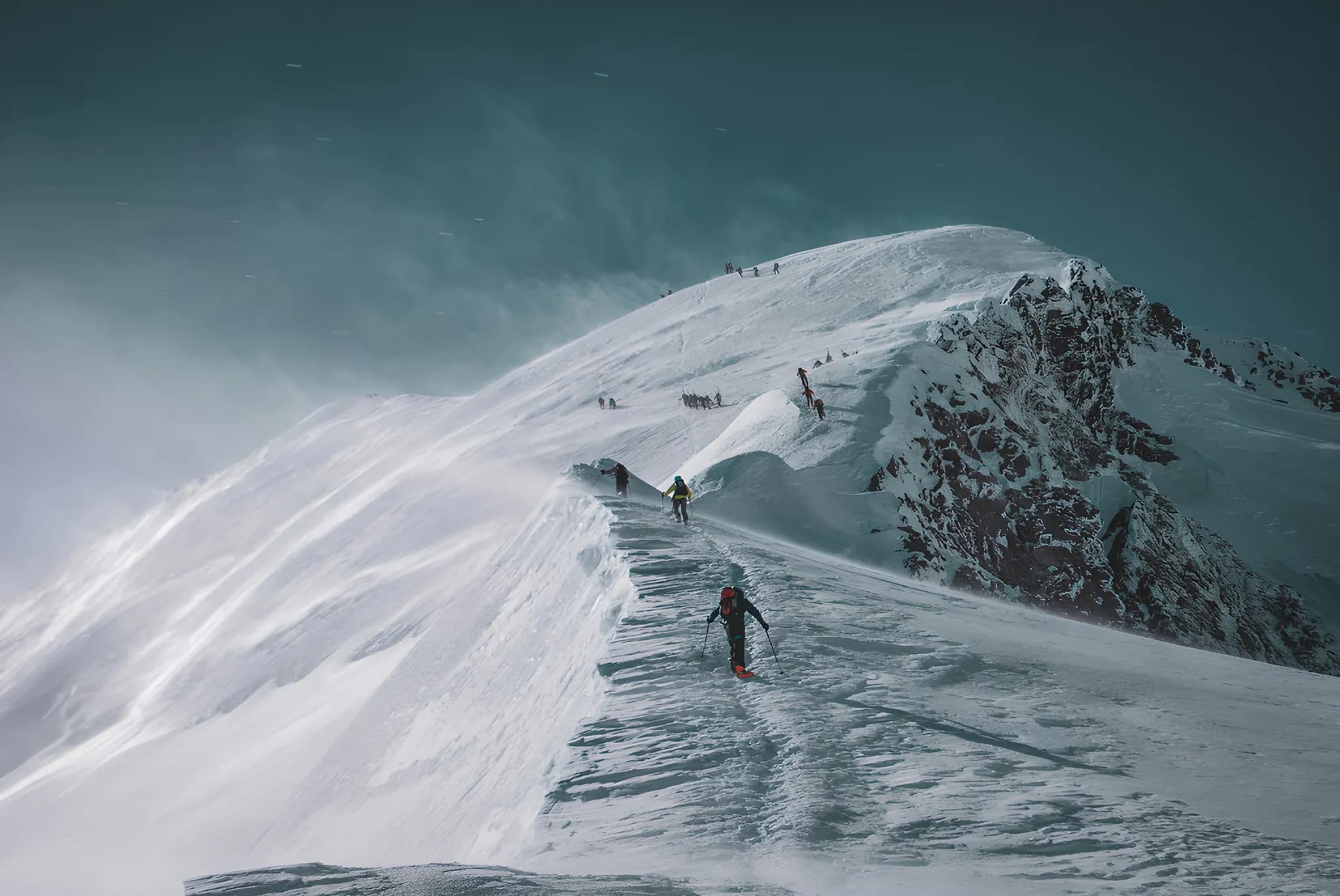 Un groupe d'alpinistes sur une crête enneigée, conquérant le sommet majestueux du Mont Blanc.