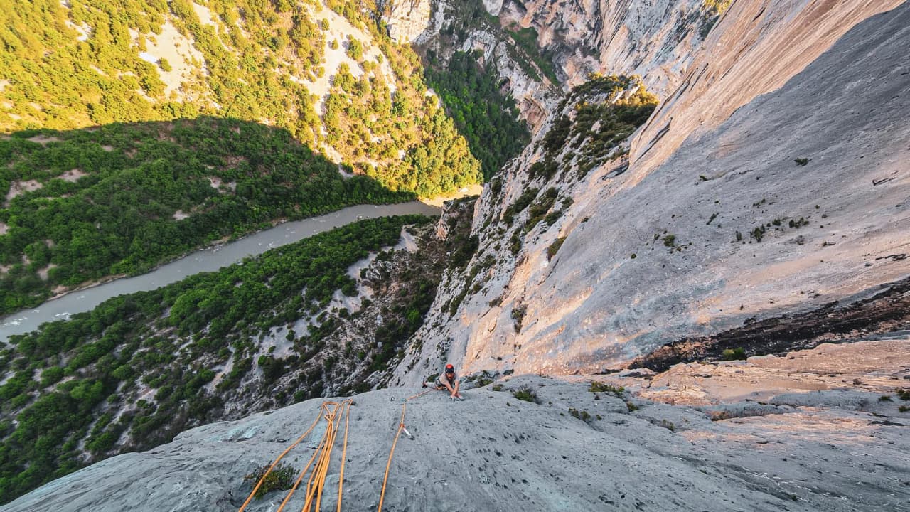 A climber emerges at the top of the cliffs in the Gorges du Verdon, surrounded by nature.