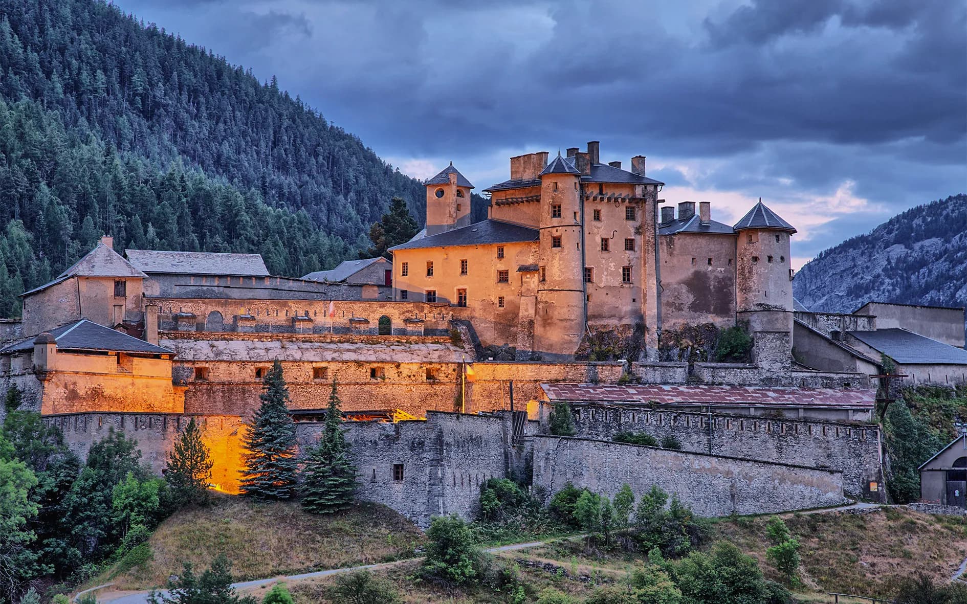 A majestic castle in the heart of the mountains, illuminated at dusk. An enchanting place to discover.