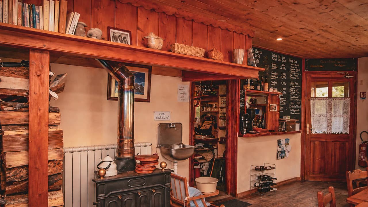 A cosy mountain hut with a wood-burning stove, books and a friendly atmosphere.