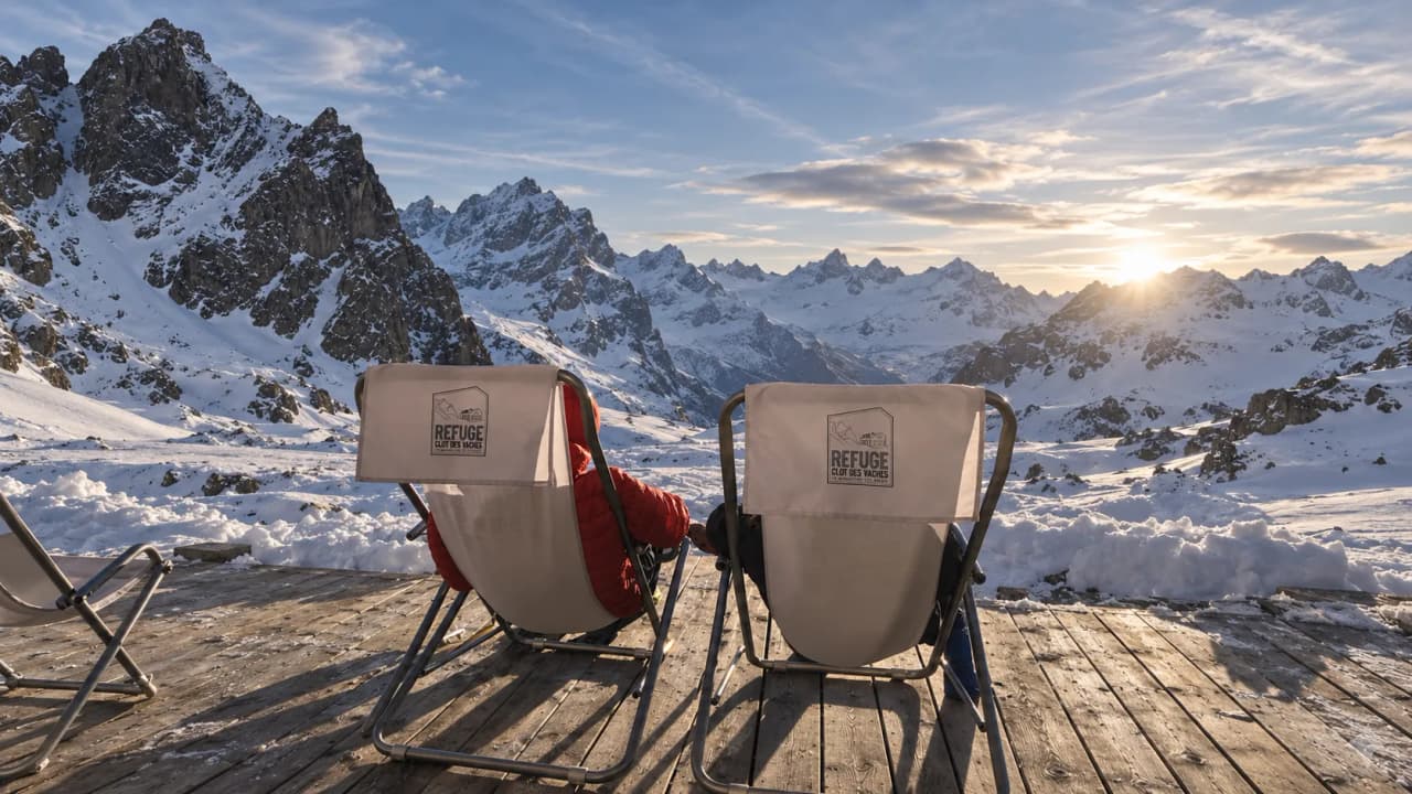 Sun loungers facing snow-capped mountains at sunset – an invitation to travel.