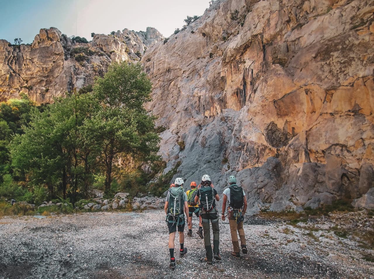 Groupe d'aventuriers marchant vers des falaises majestueuses au cœur des Pyrénées.