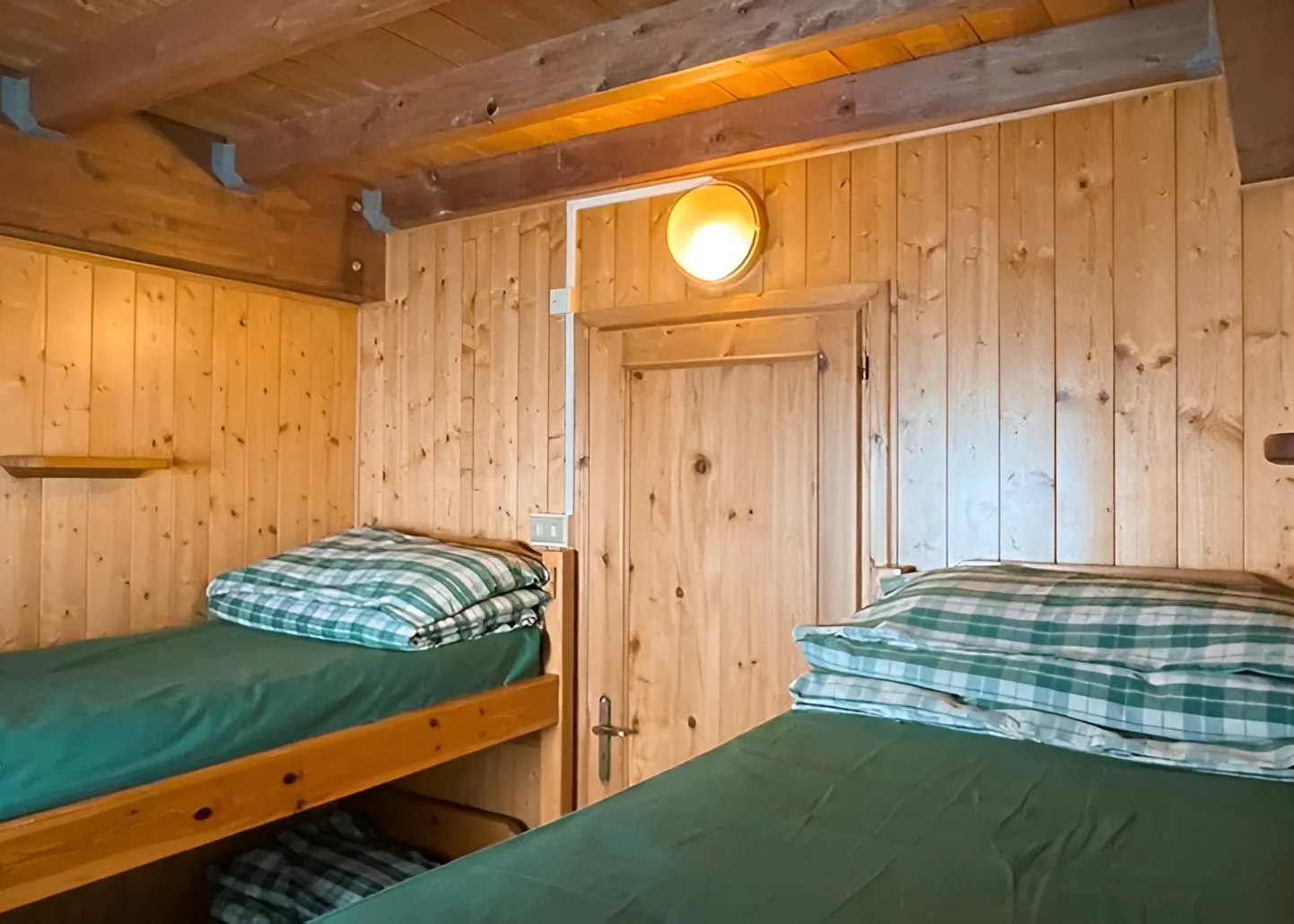 Chambre chaleureuse en bois avec lits simples, idéale pour un séjour alpin.
